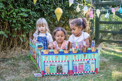 Convertible Ice Cream Shop by Miles Kelly is being played with outside by three young girls. The children are slotting the ice cream scoops onto the cones.