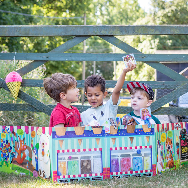 Convertible Ice Cream Shop by Miles Kelly is being played with by three young boys. They are stacking together ice creams, whilst sitting inside the shop.